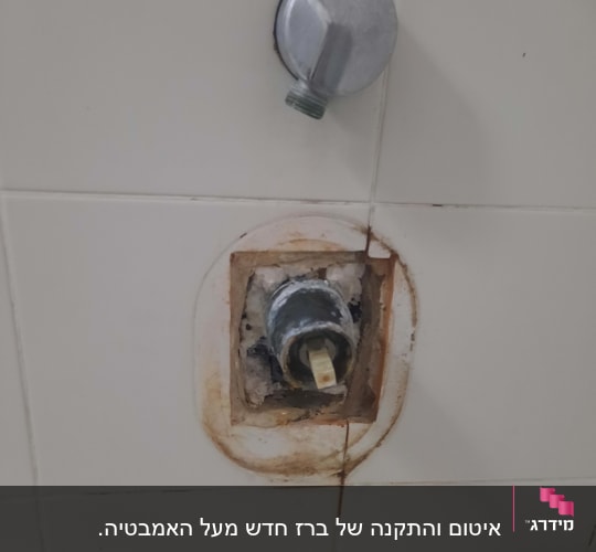 ברז מים חשוף עם חלודה על קיר אריחים